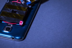 Illuminated in red is one of the 3-D printed retroreflectors, which reflects the low-power guard beams to diodes on the laser emitter. Interruption of the guard beams triggers a safety system which blocks the charging beam.