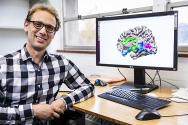 Jason Yeatman, an assistant professor in the UW Department of Speech and Hearing Sciences, shows an illustration of the brain in his office at I-LABS.