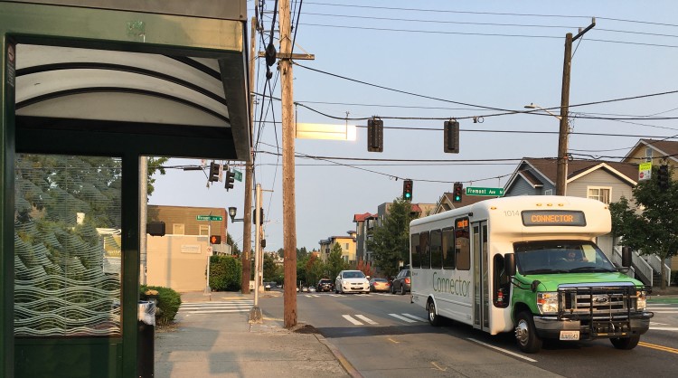 A private Microsoft shuttle drives past a King County Metro bus stop in North Seattle during the morning commute.