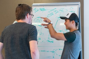 A group of scientists standing at a board discussing experiments.
