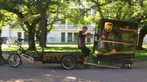 A UPS delivery person puts a cargo box on an e-bike