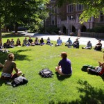 A University of Washington class meets outside of Mary Gates Hall on a sunny day. Photo of students in a circle under a tree.