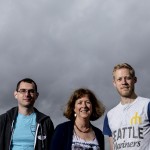 three people in front of gray sky