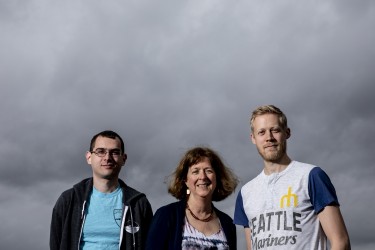 three people in front of gray sky