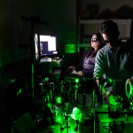Two people operating a laser to heat material and make nanodiamonds.
