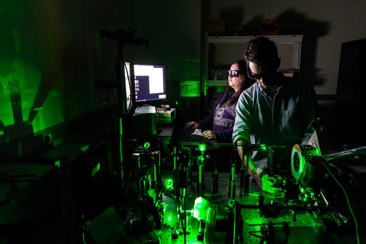 Two people operating a laser to heat material and make nanodiamonds.