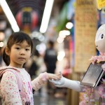 a small girl touches a robot's hand