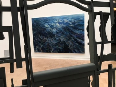 "Spoiled Landscapes - Ocean," an oil on canvas by Baorong Liang is seen through a gap in Brighton McCormack's house-like structure "Fully Furnished" (in video above) at the 2019 MFA + MDes Thesis Exhibition at the Henry Art Gallery.