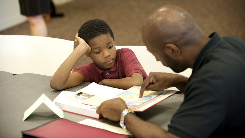 Photo of adult helping a boy in class with a paper.