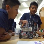 Two fifth-grade boys from Forks, WA point out design elements of their LEGO lunar rover.