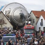 A large piece of scientific equipment being moved through a town
