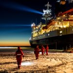 ship surrounded by sea ice and dark skies