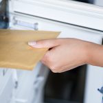 Woman's hand pulling envelop from mailbox