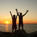 Photo of two children, in silhouette, on a beach