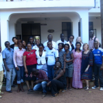 Group of people pose outside a building.