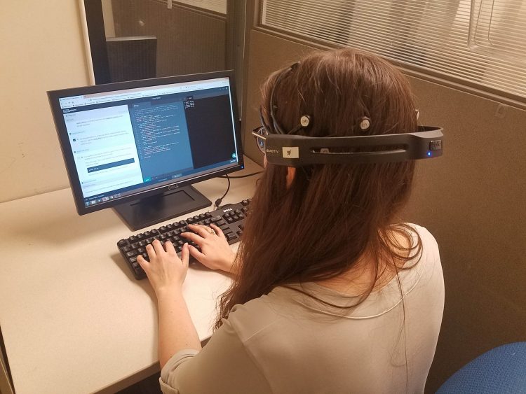 Woman working on computer, wearing headset while