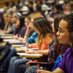 A college classroom with students seated in a lecture hall.