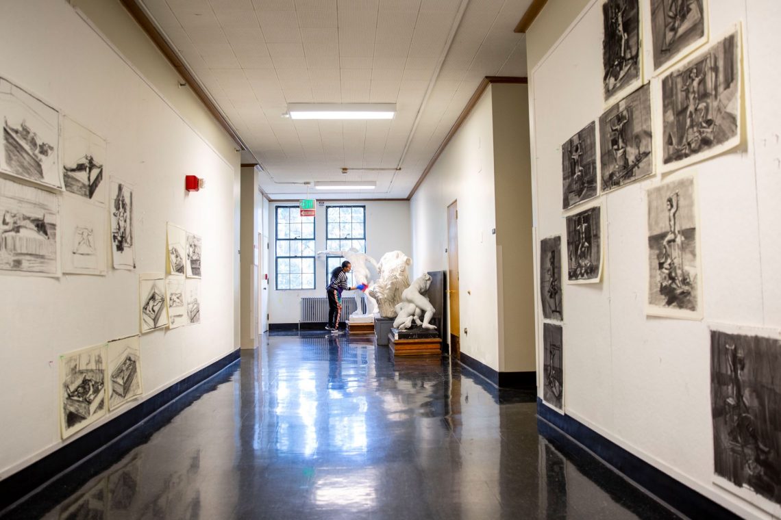 woman at end of hallways wipes sculpture