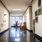 woman at end of hallways wipes sculpture