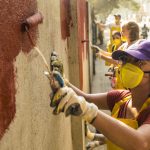 Students painting a wall a copper color