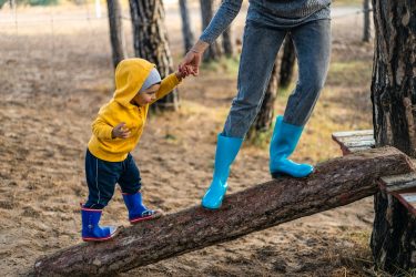 child and adult play on log
