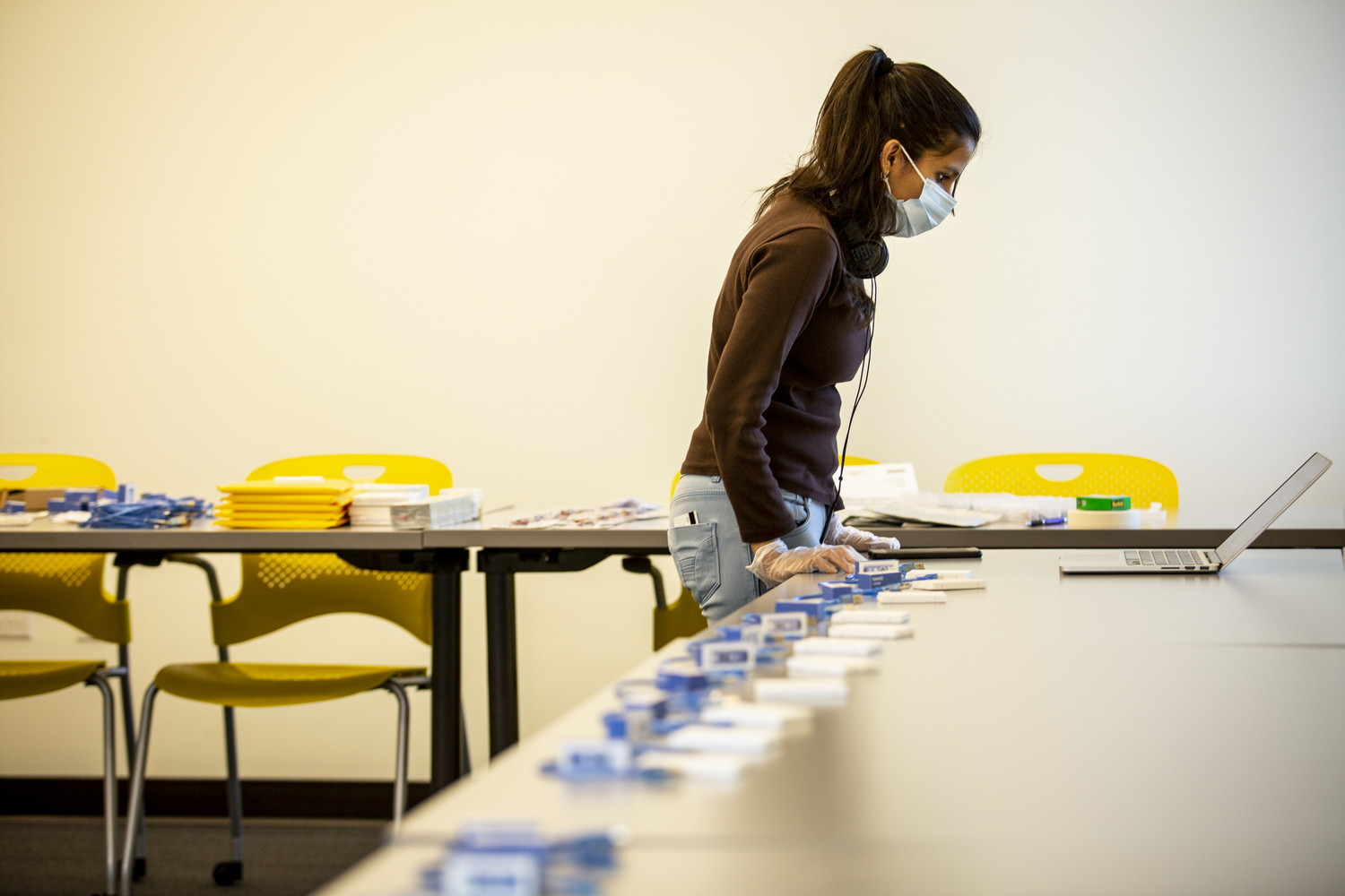 A TA looks at a laptop on a table. Also on the table, equipment for a kit.