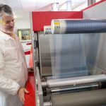 A person inside a laboratory demonstrating printer technology for flexible electronics
