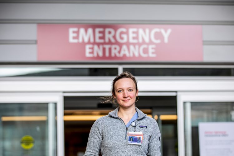 woman stands in front of Emergency entrance at hospital