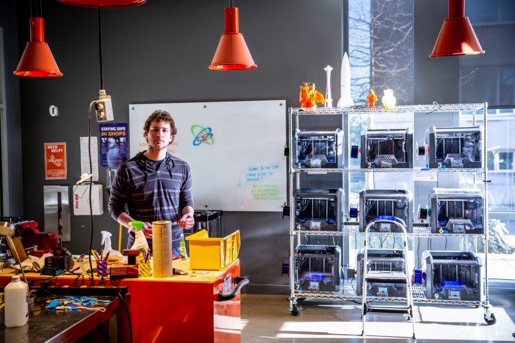 man standing a room with 3D printers near the wall