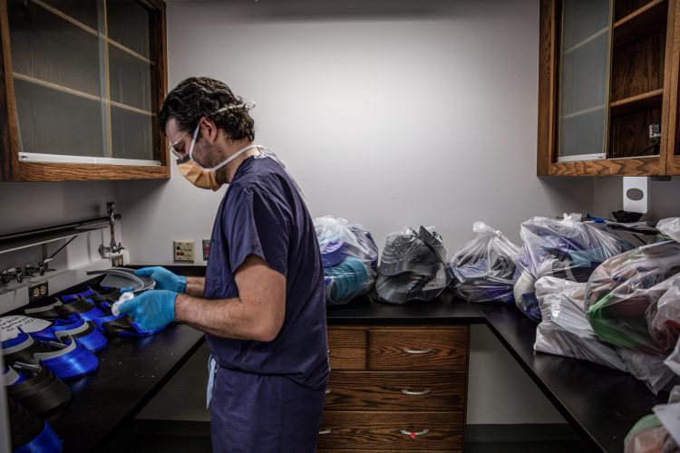 man in scrubs disinfects visors that affix to face shields