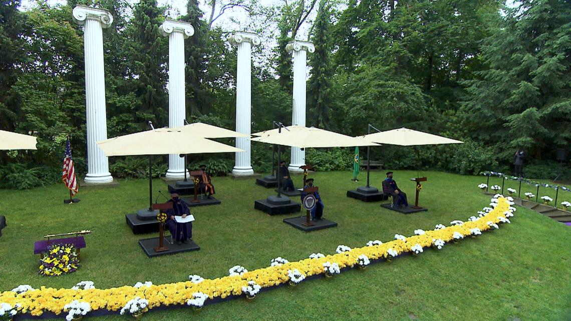 people in gowns sitting on green lawn
