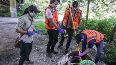 people gather around sewer drain