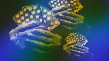 gloved hands hold packets of pills