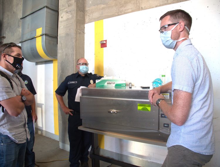 People standing around a refrigerator-sized box