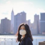 Person wearing a face mask with New York City skyline in the background