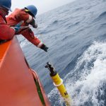 two people drop instrument in water
