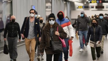people in masks walk through airport