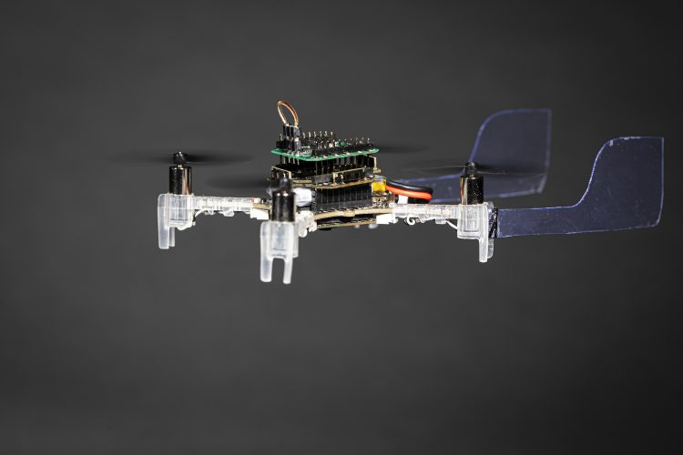 A drone hovering in midair. It has two plastic fins on its back.
