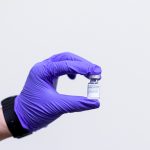 gloved hand holds vial of vaccine