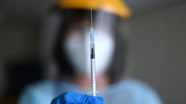person holds up syringe