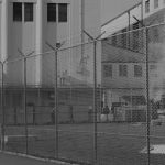 outside of prison, surrounded by razor-wire fence