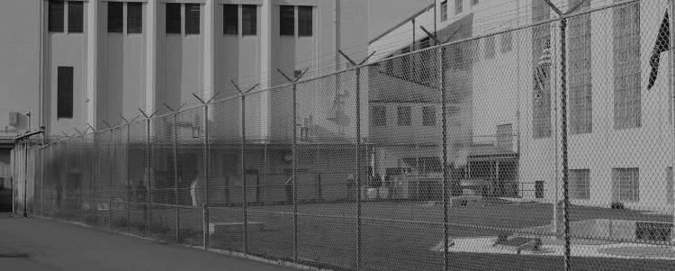 outside of prison, surrounded by razor-wire fence