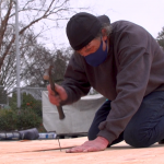 Man hammers nail into plywood platform