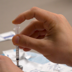 Hands filling a syringe.