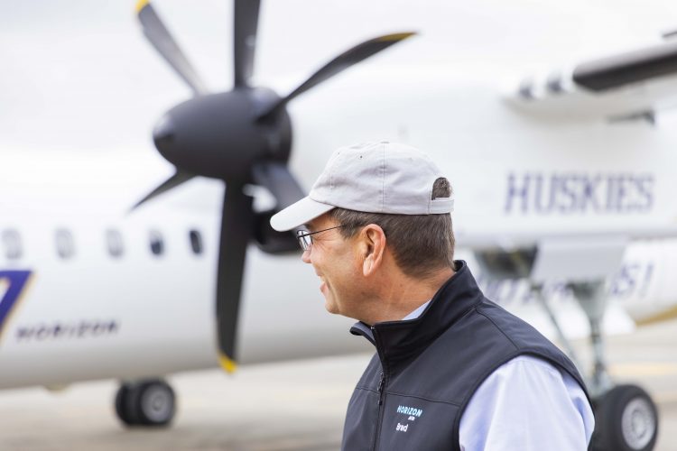 Brad Tilden, a UW alum who retired as CEO of Alaska Airlines on March 31, looks at a Horizon Air Q400 aircraft with a special UW-themed livery.
