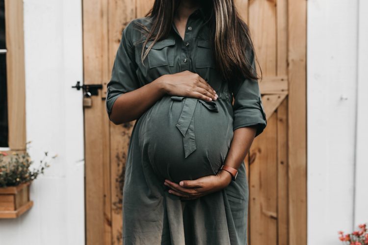 Pregnant person holds belly