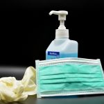 bottle of hand sanitizer, gloves and a mask on a table