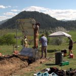 A group of men on a hill erecting a solar panel, part of seismic site being constructed in Enumclaw, Wa