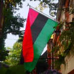 A red, black and green flag hangs outside a building.