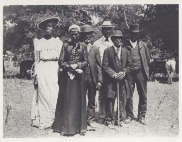 A group of people poses outside for this photo from 1900.
